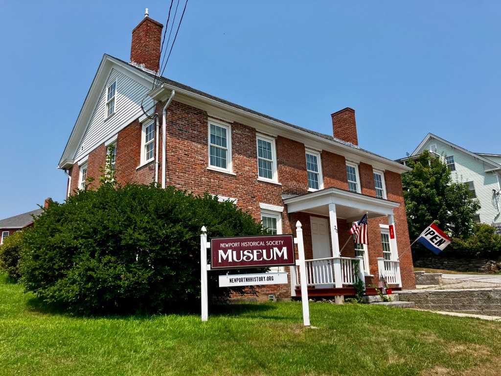 Exterior view of the Newport Historical Society Museum, featuring a brick building with a sign that reads 'Museum' and an 'Open' flag.